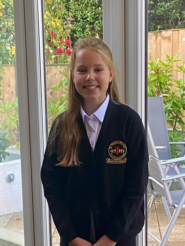 Abigail smiling in her school uniform in front of her family garden