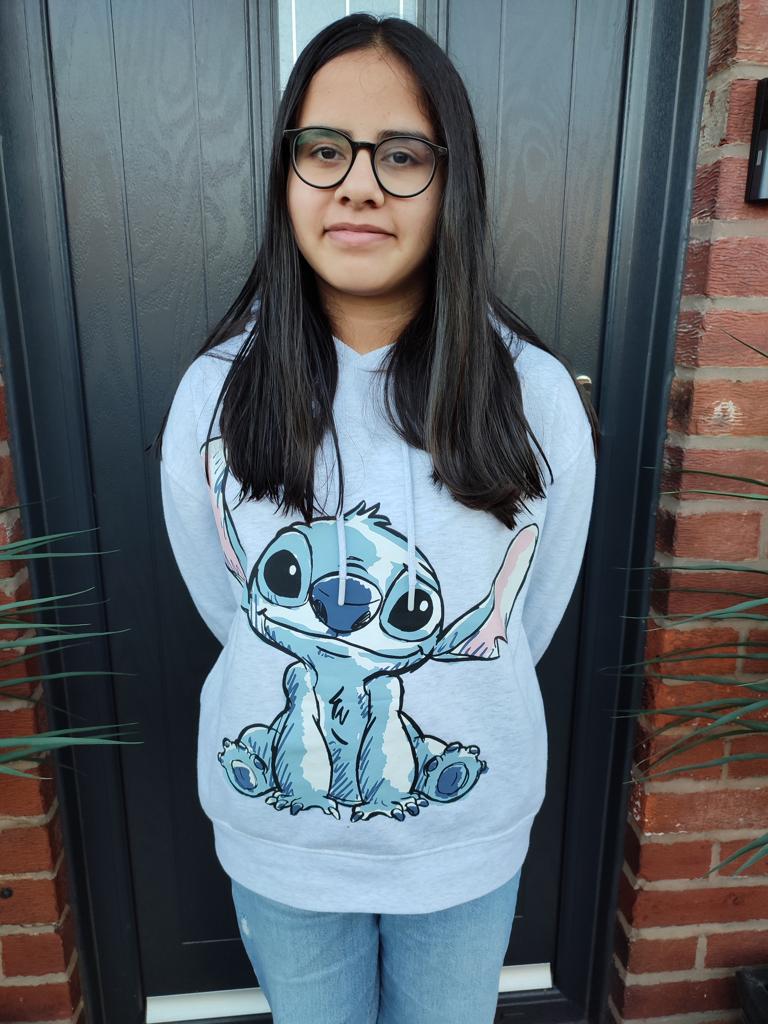 Inaya posing in front of her front door, wearing a Disney's Stitch-themed jumper