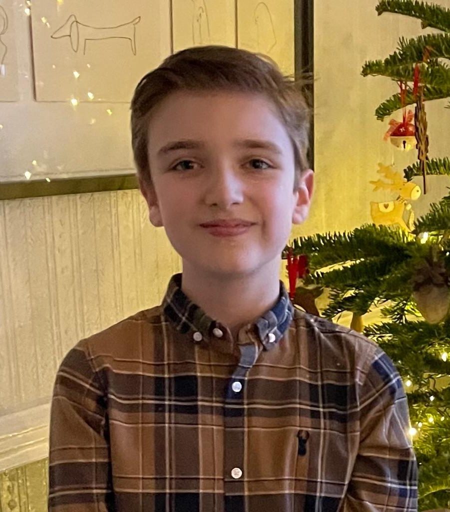 Sam smiling in front of his Christmas tree